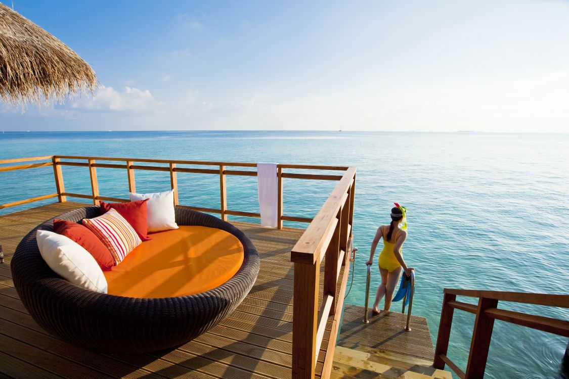 woman in blue bikini sitting on brown wooden bench near sea during daytime