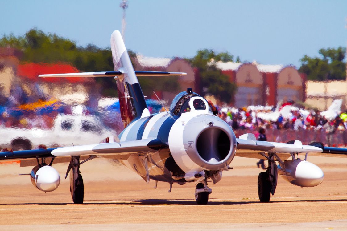 white and blue airplane on brown field during daytime