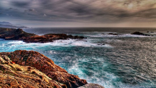 Image ocean waves crashing on rocky shore under cloudy sky