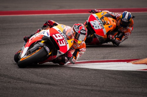 Image man in orange and black racing suit riding on sports bike