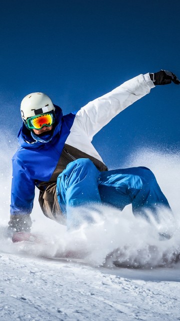 Image person in blue and white snow suit riding on white snow mobile during daytime