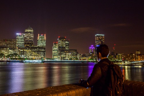 Image man in black jacket sitting on brown wooden dock during night time