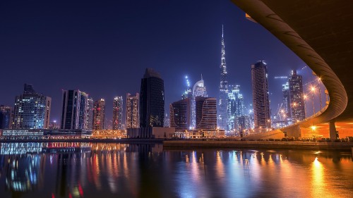 Image city skyline across body of water during night time