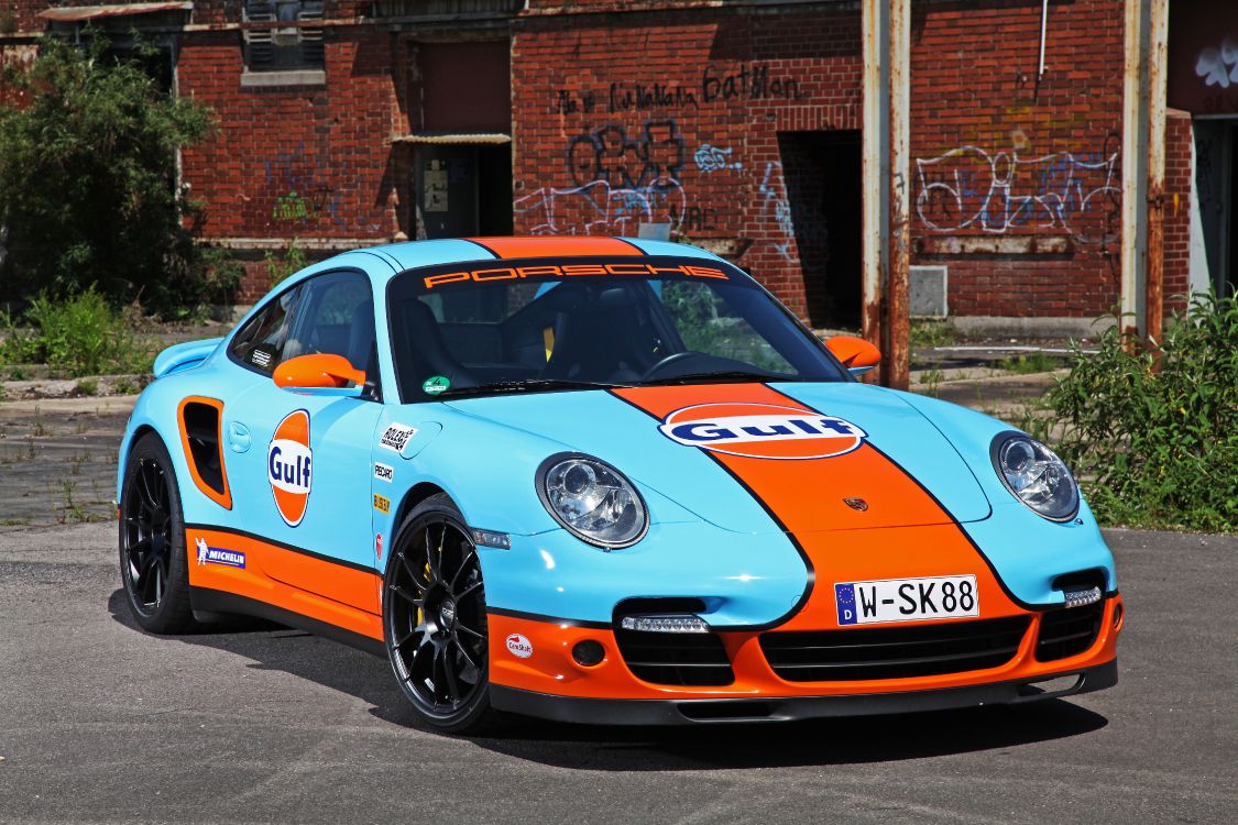 Blau-weißer Porsche 911 Geparkt in Der Nähe Eines Braunen Backsteingebäudes Tagsüber. Wallpaper in 5616x3744 Resolution