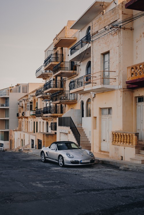 Image white porsche 911 parked beside yellow concrete building during daytime