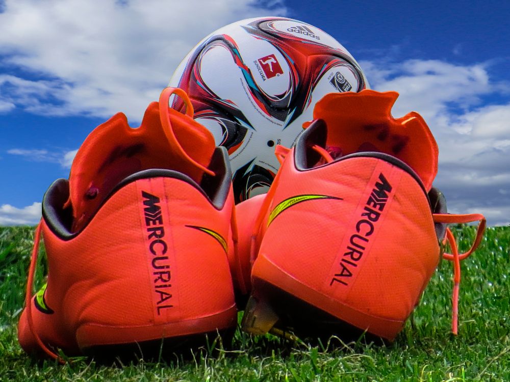 orange and white nike athletic shoes on green grass during daytime