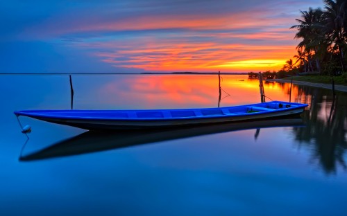 Image white and blue boat on water during sunset