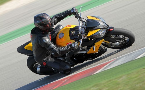 Image man in black and yellow suit riding orange sports bike