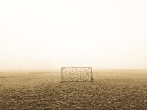 Image white and black soccer goal on field covered with fog