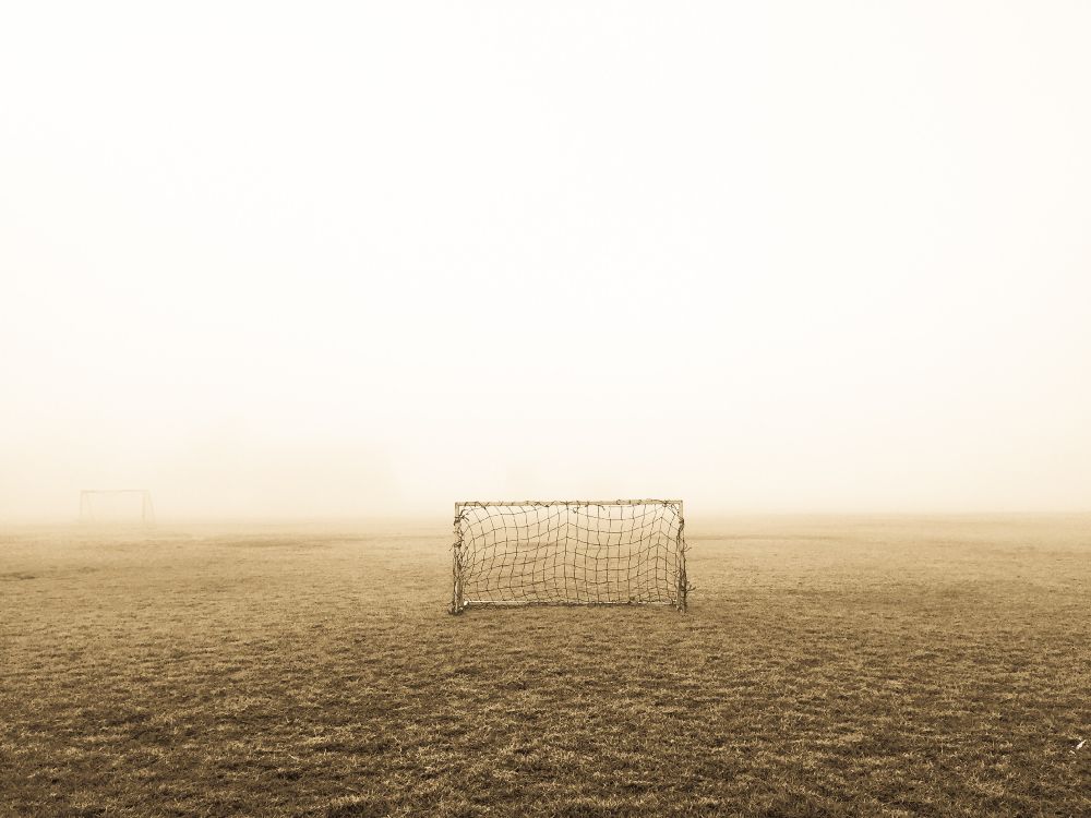 white and black soccer goal on field covered with fog