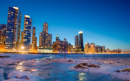 Image city skyline across body of water during night time