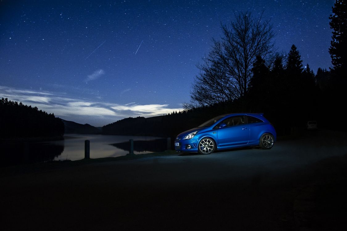 blue sedan parked near tree during night time