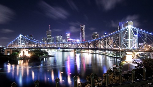 Image people sitting on bench near bridge during night time