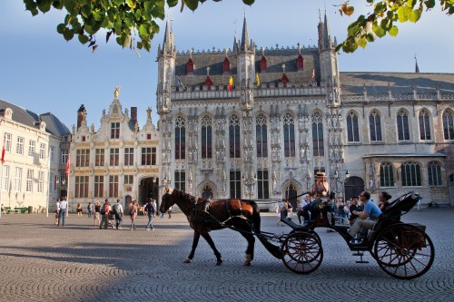 Image people riding horses in front of white concrete building during daytime