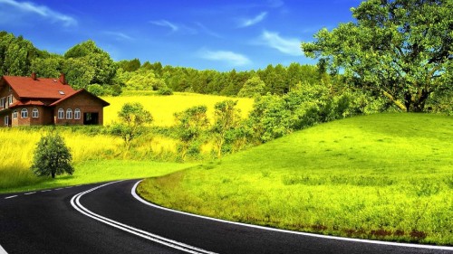 Image black asphalt road between green grass field under blue sky during daytime