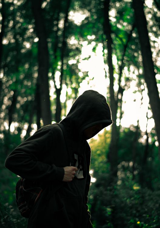 man in black hoodie standing in forest during daytime