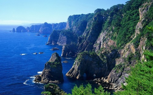 Image green and brown mountain beside blue sea under blue sky during daytime