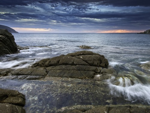 Image brown rock formation on sea under blue sky during daytime