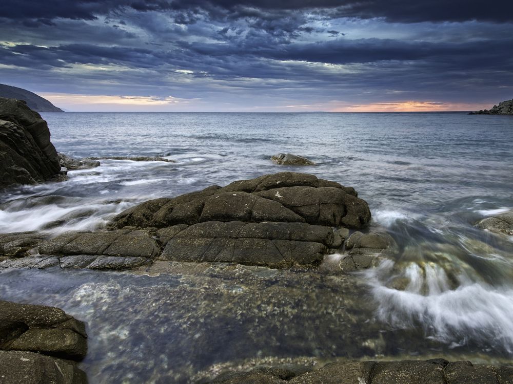 brown rock formation on sea under blue sky during daytime