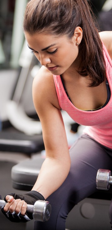 Image woman in pink tank top holding dumbbell