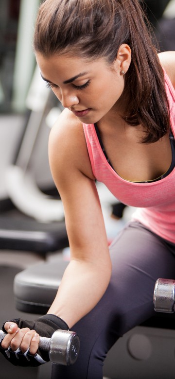 Image woman in pink tank top holding dumbbell