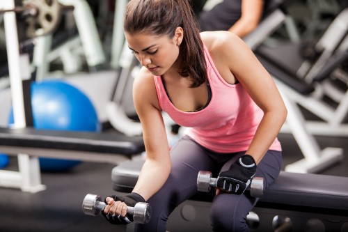 Image woman in pink tank top holding dumbbell