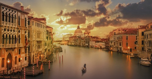 Image boat on water near buildings during sunset