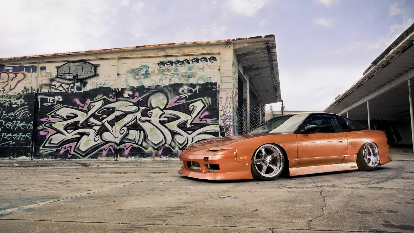 Porsche 911 Naranja Estacionado Junto a la Pared Con Graffiti. Wallpaper in 2500x1406 Resolution