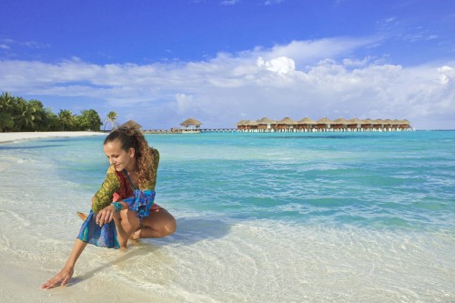 Image girl in blue and white polka dot dress sitting on beach shore during daytime