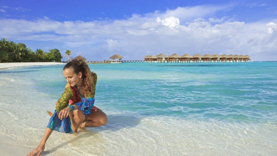 Image girl in blue and white polka dot dress sitting on beach shore during daytime