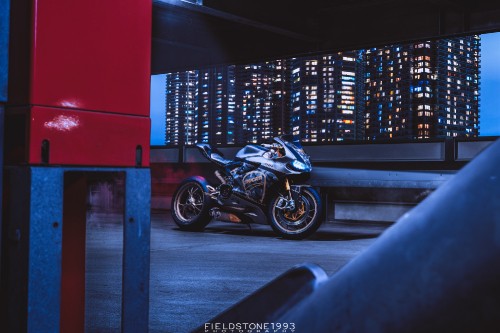 Image black and silver motorcycle parked beside red wall