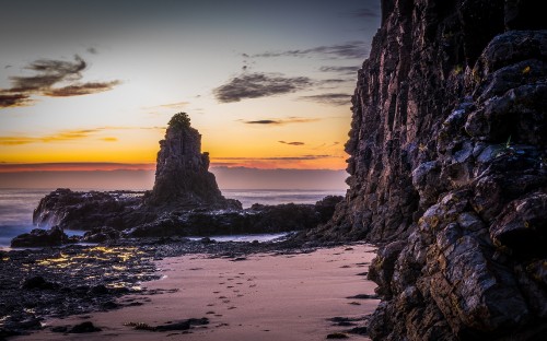 Image brown rock formation on sea shore during sunset