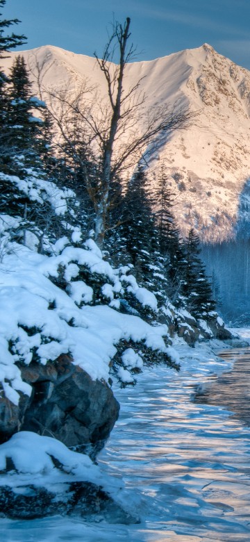 Image snow covered mountain near body of water during daytime