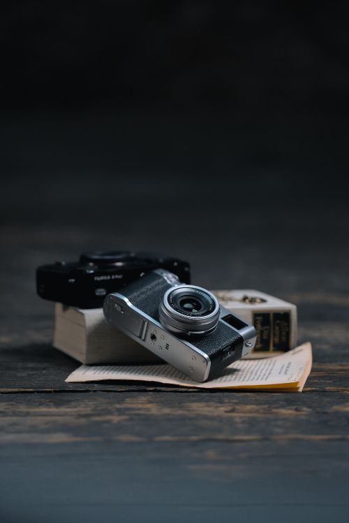 Schwarze Und Silberne Kamera Auf Braunem Buch. Wallpaper in 4160x6240 Resolution