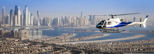 Image white and blue helicopter flying over city buildings during daytime