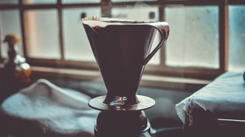 Image clear glass mug with brown liquid on white ceramic saucer