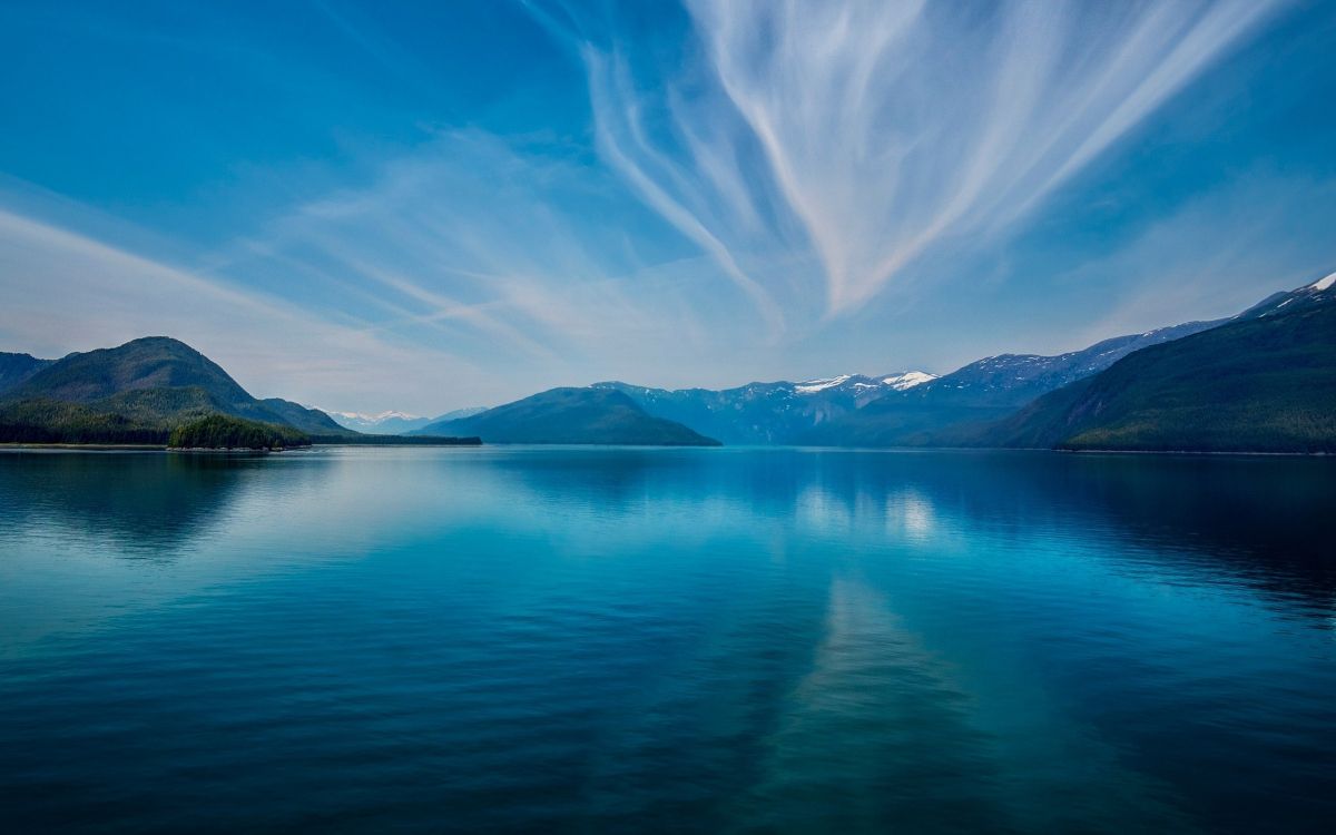blue body of water near mountain under blue sky during daytime