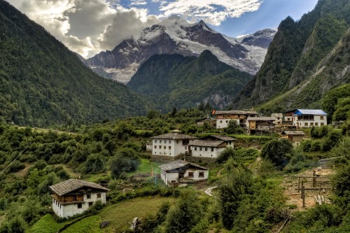 Image white and brown concrete building near green trees and mountains during daytime