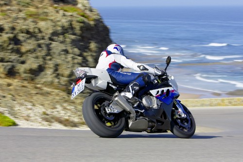 Image man in white and black motorcycle suit riding on white and blue sports bike