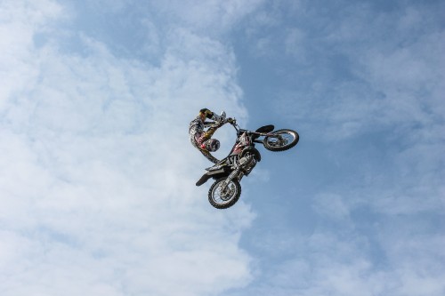 Image man riding on bicycle doing stunts under blue sky during daytime