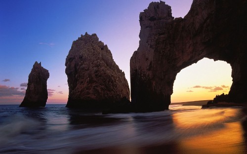 Image brown rock formation on sea shore during sunset