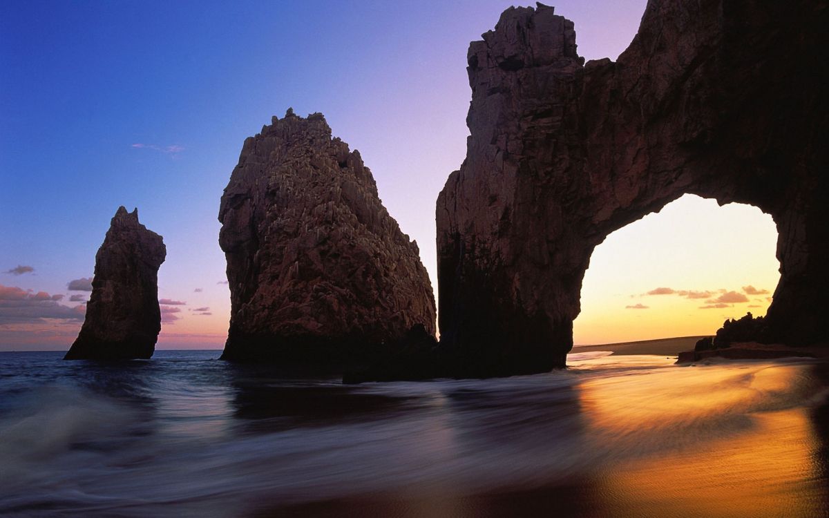 brown rock formation on sea shore during sunset