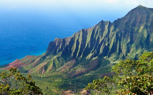 Image green and brown mountains beside blue sea under blue sky during daytime