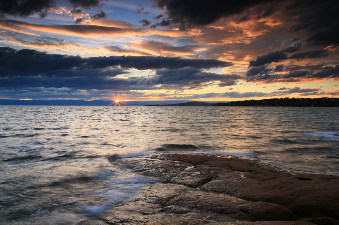 sea waves crashing on shore during sunset