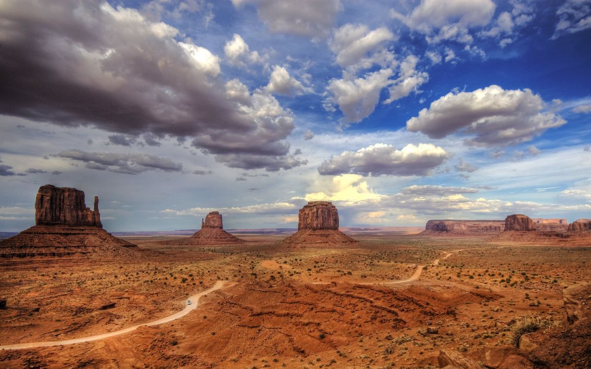 brown sand under white clouds and blue sky during daytime