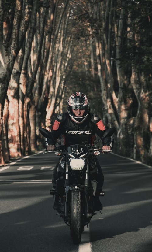 Image man in black and red motorcycle suit riding motorcycle on road during daytime