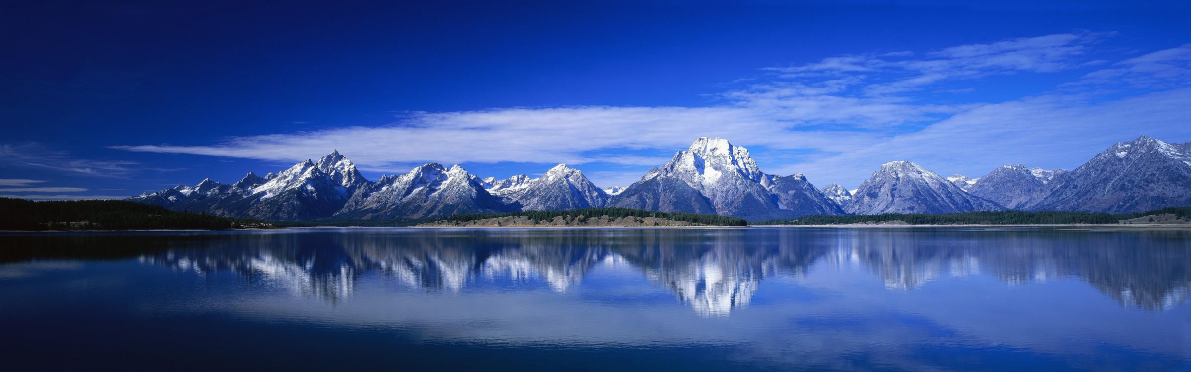 snow covered mountain near body of water during daytime