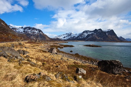 Image green grass field near body of water and mountains under blue sky during daytime