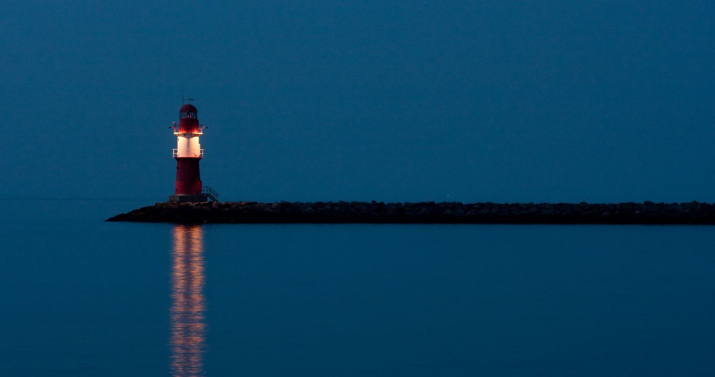 Faro Blanco y Rojo Cerca Del Cuerpo de Agua Durante la Noche.. Wallpaper in 3477x1836 Resolution