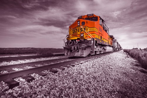 Image yellow and red train on rail tracks under cloudy sky